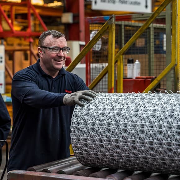 A Tensar employee in the warehouse holding Tensar InterAx (NX) Geogrids